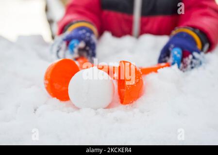 Appareil pour sculpter les boules de neige dans les mains des enfants sur fond de neige Banque D'Images