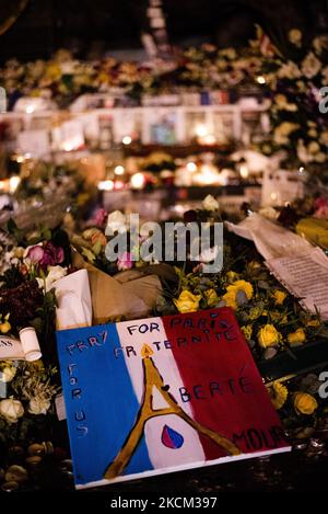 Sur 26 novembre 2015, près de deux semaines après les attaques de 13 novembre 2015 qui ont fait 130 morts et plus de 400 blessés dans une série d'attaques qui ont touché plusieurs endroits à Paris, y compris le Stade de France, Terrasses de café et salle de concert Bataclan l'émotion est toujours présente dans les rues de Paris, Comme ici, sur la place de la République, où de nombreux Parisiens continuent de se rassembler pour partager leur émotion et rendre hommage aux victimes devant la statue de la République dont la base est toujours remplie de fleurs, de bougies et de messages de paix. (Photo de Samuel Boivin/NurPhoto) Banque D'Images