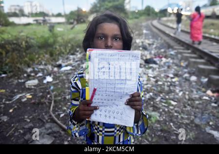Une fille de taudis tient sa copie où elle a écrit le nom de base des jours d'une semaine comme sa leçon lors d'une classe privée prise par une police de Kolkata le jour de la Journée internationale de l'alphabétisation à Kolkata, Inde, 08 septembre 2021. (Photo par Indranil Aditya/NurPhoto) Banque D'Images