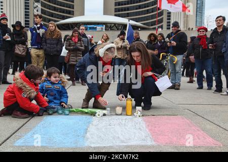 14 novembre 2015, Toronto, Ontario, Canada --- les Canadiens placent des bougies et des fleurs par un drapeau français lors d'une veillée à Nathan Phillips Square à Toronto, Canada, pour manifester leur solidarité avec les citoyens de la France un jour après les attentats terroristes de Paris. Les jihadistes de l'État islamique ont revendiqué une série d'attaques coordonnées perpétrées par des hommes armés et des kamikazes à Paris contre 13 novembre, qui ont tué au moins 129 personnes et blessé plus de 350 personnes dans des scènes de carnage dans une salle de concert, dans des restaurants et dans le stade national. Cette attaque est l'attaque la plus meurtrière de Paris depuis la Seconde Guerre mondiale. --- (photo de Creative T Banque D'Images