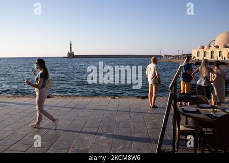 Les habitants et les touristes sont vus avec facemask à pied à la promenade du front de mer de l'ancien port vénitien de la ville de Chania avec les petites boutiques, tavernes, cafés et restaurants autour ainsi que le célèbre phare, la mosquée, les chantiers navals vénitiens et les monuments anciens et les monuments près du port et de la mer Égée. La Grèce tente de stimuler son tourisme et de donner des privilèges pour se faire vacciner contre la pandémie du coronavirus Covid-19, les touristes internationaux et les habitants, car le pays est fortement tributaire de l'industrie du tourisme et des voyages malgré le nombre inquiétant de cas avec le Coro Covid-19 Banque D'Images