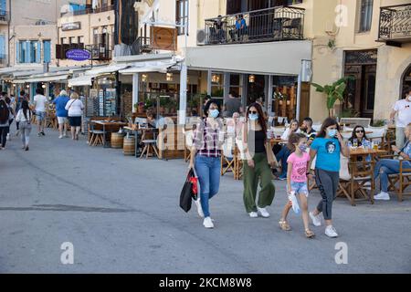 Les habitants et les touristes sont vus avec facemask à pied à la promenade du front de mer de l'ancien port vénitien de la ville de Chania avec les petites boutiques, tavernes, cafés et restaurants autour ainsi que le célèbre phare, la mosquée, les chantiers navals vénitiens et les monuments anciens et les monuments près du port et de la mer Égée. La Grèce tente de stimuler son tourisme et de donner des privilèges pour se faire vacciner contre la pandémie du coronavirus Covid-19, les touristes internationaux et les habitants, car le pays est fortement tributaire de l'industrie du tourisme et des voyages malgré le nombre inquiétant de cas avec le Coro Covid-19 Banque D'Images