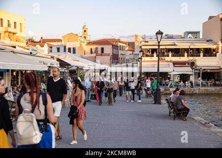 Les habitants et les touristes sont vus avec facemask à pied à la promenade du front de mer de l'ancien port vénitien de la ville de Chania avec les petites boutiques, tavernes, cafés et restaurants autour ainsi que le célèbre phare, la mosquée, les chantiers navals vénitiens et les monuments anciens et les monuments près du port et de la mer Égée. La Grèce tente de stimuler son tourisme et de donner des privilèges pour se faire vacciner contre la pandémie du coronavirus Covid-19, les touristes internationaux et les habitants, car le pays est fortement tributaire de l'industrie du tourisme et des voyages malgré le nombre inquiétant de cas avec le Coro Covid-19 Banque D'Images