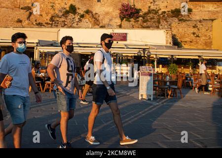 Les habitants et les touristes sont vus avec facemask à pied à la promenade du front de mer de l'ancien port vénitien de la ville de Chania avec les petites boutiques, tavernes, cafés et restaurants autour ainsi que le célèbre phare, la mosquée, les chantiers navals vénitiens et les monuments anciens et les monuments près du port et de la mer Égée. La Grèce tente de stimuler son tourisme et de donner des privilèges pour se faire vacciner contre la pandémie du coronavirus Covid-19, les touristes internationaux et les habitants, car le pays est fortement tributaire de l'industrie du tourisme et des voyages malgré le nombre inquiétant de cas avec le Coro Covid-19 Banque D'Images