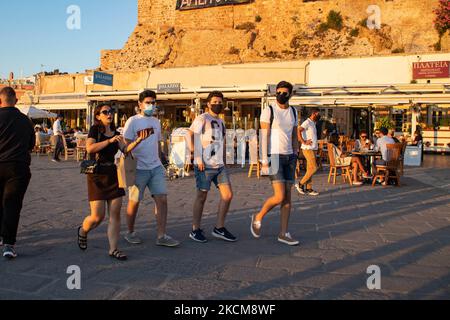 Les habitants et les touristes sont vus avec facemask à pied à la promenade du front de mer de l'ancien port vénitien de la ville de Chania avec les petites boutiques, tavernes, cafés et restaurants autour ainsi que le célèbre phare, la mosquée, les chantiers navals vénitiens et les monuments anciens et les monuments près du port et de la mer Égée. La Grèce tente de stimuler son tourisme et de donner des privilèges pour se faire vacciner contre la pandémie du coronavirus Covid-19, les touristes internationaux et les habitants, car le pays est fortement tributaire de l'industrie du tourisme et des voyages malgré le nombre inquiétant de cas avec le Coro Covid-19 Banque D'Images