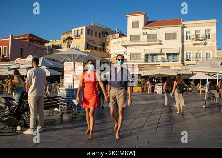 Les habitants et les touristes sont vus avec facemask à pied à la promenade du front de mer de l'ancien port vénitien de la ville de Chania avec les petites boutiques, tavernes, cafés et restaurants autour ainsi que le célèbre phare, la mosquée, les chantiers navals vénitiens et les monuments anciens et les monuments près du port et de la mer Égée. La Grèce tente de stimuler son tourisme et de donner des privilèges pour se faire vacciner contre la pandémie du coronavirus Covid-19, les touristes internationaux et les habitants, car le pays est fortement tributaire de l'industrie du tourisme et des voyages malgré le nombre inquiétant de cas avec le Coro Covid-19 Banque D'Images