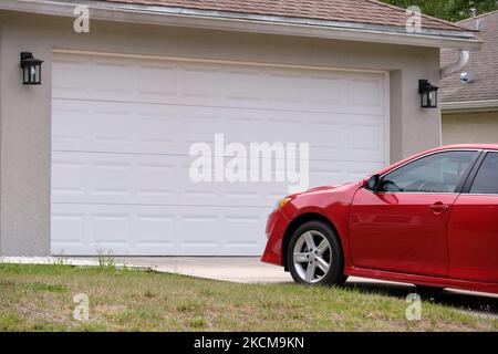 Véhicule stationné devant un grand garage double porte sur une allée pavée d'une maison américaine contemporaine typique Banque D'Images