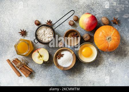 Fond de cuisson des aliments. Citrouilles, pommes, miel, noix et épices de saison pour la citrouille ou la tarte aux pommes sur un plan d'examen gris. Vue de dessus. Banque D'Images