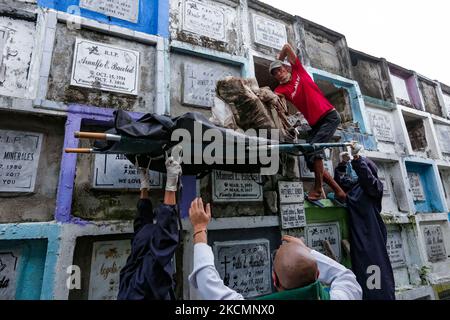 NAVOTAS CITY, Philippines - Un travailleur place les restes d'une victime présumée de la guerre de la drogue dans un sac de corps car ils s'exhument des restes au cimetière de Navotas sur 17 septembre 2021. Plusieurs vestiges ont été exhumés à l'expiration du bail sur leurs tombes. Au 15 septembre dernier, la Cour pénale internationale (CPI) a autorisé une enquête sur le Président Duterte et sa guerre contre la drogue depuis son entrée en fonction le 2016 juillet jusqu'à ce que le 16 mars 2019, lorsque le pays s'est retiré du Statut de Rome qui a créé la CPI, prenne effet. L'enquête portera également sur les meurtres commis dans la ville de Davao, où le président Duterte a servi bo Banque D'Images