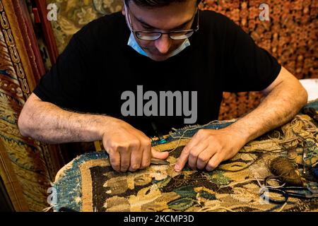 Saint-Ouen, France, le 18 juillet 2021. Un marchand d'antiquités restaure un tapis dans son magasin au marché de Biron dans le marché aux puces de Saint-Ouen. Beaucoup de restaurateurs donnent une nouvelle vie à quelques antiquités sur place. Banque D'Images