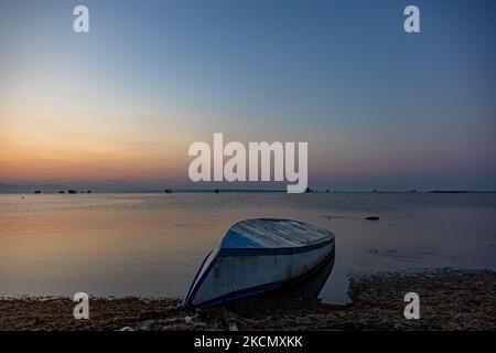 Un petit bateau de pêche sur la rive. Lever du soleil, l'aube et le soleil se reflétant sur la mer au Parc National du Delta d'Axios, un emplacement avec des zones humides près de Halastra et de la ville de Thessalonique où 4 fleuves Gallikos, Axios, Loudias et Aliakomnas ont leur delta. À l'endroit précis, les pêcheurs et les producteurs de moules ont leurs huttes et leurs bateaux. Au sujet de la biodiversité, cette région est célèbre et d'importance ornithologique mondiale, car des populations considérables d'oiseaux rares s'arrêtent, nichent ou hivernent ici, tandis que 299 espèces d'oiseaux ont été documentées. Comme sur flore et faune plus de 370 espèces de plantes h Banque D'Images