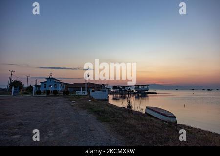 Un petit bateau de pêche sur la rive. Lever du soleil, l'aube et le soleil se reflétant sur la mer au Parc National du Delta d'Axios, un emplacement avec des zones humides près de Halastra et de la ville de Thessalonique où 4 fleuves Gallikos, Axios, Loudias et Aliakomnas ont leur delta. À l'endroit précis, les pêcheurs et les producteurs de moules ont leurs huttes et leurs bateaux. Au sujet de la biodiversité, cette région est célèbre et d'importance ornithologique mondiale, car des populations considérables d'oiseaux rares s'arrêtent, nichent ou hivernent ici, tandis que 299 espèces d'oiseaux ont été documentées. Comme sur flore et faune plus de 370 espèces de plantes h Banque D'Images