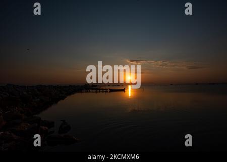 Photographie en exposition longue du lever du soleil, de l'aube et du soleil se reflétant sur la mer au Parc National du Delta d'Axios, un endroit avec des zones humides près de Halastra et de la ville de Thessalonique où 4 rivières Gallikos, Axios, Loudias et Aliakomnas ont leur delta. À l'endroit précis, les pêcheurs et les producteurs de moules ont leurs huttes et leurs bateaux. Au sujet de la biodiversité, cette région est célèbre et d'importance ornithologique mondiale, car des populations considérables d'oiseaux rares s'arrêtent, nichent ou hivernent ici, tandis que 299 espèces d'oiseaux ont été documentées. Comme au sujet de flore et de faune plus de 370 espèces de plantes ont Banque D'Images