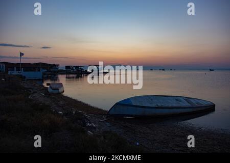 Un petit bateau de pêche sur la rive. Lever du soleil, l'aube et le soleil se reflétant sur la mer au Parc National du Delta d'Axios, un emplacement avec des zones humides près de Halastra et de la ville de Thessalonique où 4 fleuves Gallikos, Axios, Loudias et Aliakomnas ont leur delta. À l'endroit précis, les pêcheurs et les producteurs de moules ont leurs huttes et leurs bateaux. Au sujet de la biodiversité, cette région est célèbre et d'importance ornithologique mondiale, car des populations considérables d'oiseaux rares s'arrêtent, nichent ou hivernent ici, tandis que 299 espèces d'oiseaux ont été documentées. Comme sur flore et faune plus de 370 espèces de plantes h Banque D'Images