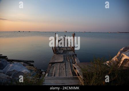 Petite jetée en bois pour les bateaux de pêche. Lever du soleil, l'aube et le soleil se reflétant sur la mer au Parc National du Delta d'Axios, un emplacement avec des zones humides près de Halastra et de la ville de Thessalonique où 4 fleuves Gallikos, Axios, Loudias et Aliakomnas ont leur delta. À l'endroit précis, les pêcheurs et les producteurs de moules ont leurs huttes et leurs bateaux. Au sujet de la biodiversité, cette région est célèbre et d'importance ornithologique mondiale, car des populations considérables d'oiseaux rares s'arrêtent, nichent ou hivernent ici, tandis que 299 espèces d'oiseaux ont été documentées. Comme sur flore et faune plus de 370 espèces de pl Banque D'Images