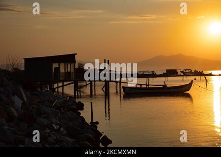 Huttes de fortune pour pêcheurs au bord de la côte. Lever du soleil, l'aube et le soleil se reflétant sur la mer au Parc National du Delta d'Axios, un emplacement avec des zones humides près de Halastra et de la ville de Thessalonique où 4 fleuves Gallikos, Axios, Loudias et Aliakomnas ont leur delta. À l'endroit précis, les pêcheurs et les producteurs de moules ont leurs huttes et leurs bateaux. Au sujet de la biodiversité, cette région est célèbre et d'importance ornithologique mondiale, car des populations considérables d'oiseaux rares s'arrêtent, nichent ou hivernent ici, tandis que 299 espèces d'oiseaux ont été documentées. Comme sur flore et faune plus de 370 Banque D'Images