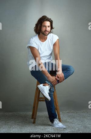 Rencontrez le maître de la cool et décontracté. Studio portrait d'un beau jeune homme posant sur un fond gris. Banque D'Images