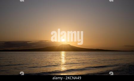 Soleil levant sur le sommet de l'île Rangitoto. Milford Beach, Auckland. Banque D'Images