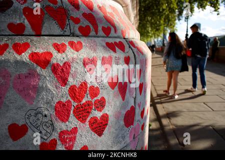 Les gens marchent à côté du mur national du Covid sur le sentier de la rive sud de la Tamise, en face du Parlement à Londres, en Angleterre, sur 27 septembre 2021. Le mur, créé ce printemps, se compose de plus de 150 000 coeurs peints, chacun représentant une vie perdue dans le pays à Covid-19. (Photo de David Cliff/NurPhoto) Banque D'Images