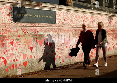 Une promenade en couple à côté du mur commémoratif national des Covid, sur le sentier de la rive sud de la Tamise, en face du Parlement à Londres, en Angleterre, sur 27 septembre 2021. Le mur, créé ce printemps, se compose de plus de 150 000 coeurs peints, chacun représentant une vie perdue dans le pays à Covid-19. (Photo de David Cliff/NurPhoto) Banque D'Images