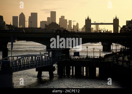 Une place du Canada (avec un toit pointu) et d'autres tours du quartier financier de Canary Wharf, ainsi que Tower Bridge, sont silhoueted en plein soleil tôt le matin, vu vers l'est le long de la Tamise, après le pont Southwark à Londres, en Angleterre, sur 11 octobre 2021. (Photo de David Cliff/NurPhoto) Banque D'Images