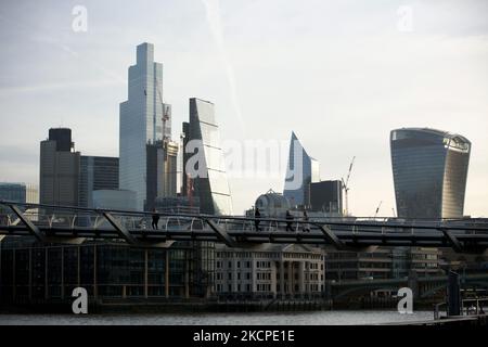 Les gens traversent le pont du millénaire en traversant la Tamise en tant que tours du quartier financier de la ville de Londres, y compris la Tour 42 (2L), le 22 Bishopsgate (L), le Leadenhall Building ou « Cheesegrater » (C), Le Scalpel (R) et le 20 Fenchurch Street ou le 'Walkie Talkie' (2R) se tiennent en plein soleil du matin à Londres, en Angleterre, sur 11 octobre 2021. (Photo de David Cliff/NurPhoto) Banque D'Images