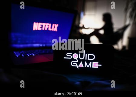 Le logo de la série de jeux Squid est affiché sur l'écran d'un téléphone, le logo Netflix sur l'écran d'un ordinateur portable et la silhouette d'une femme en arrière-plan sont illustrés sur cette photo prise à Cracovie, en Pologne, sur 18 octobre 2021. (Photo de Jakub Porzycki/NurPhoto) Banque D'Images