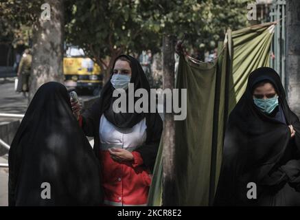 Une femme du Croissant-Rouge iranien (C) portant un masque facial de protection vérifie la température corporelle d'une femme voilée à l'entrée de l'Université de Téhéran, lors des cérémonies de prières du vendredi, au cours de la nouvelle épidémie de coronavirus (COVID-19) en Iran, au 22 octobre 2021. Les prières du vendredi de Téhéran se sont de nouveau tenues à l’Université de Téhéran vingt mois après l’épidémie de COVID-19 en Iran. (Photo de Morteza Nikoubazl/NurPhoto) Banque D'Images