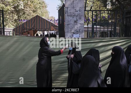 Une femme du Croissant-Rouge iranien (L) portant un masque facial de protection vérifie la température corporelle d'une femme voilée à l'entrée de l'Université de Téhéran, lors des cérémonies de prières du vendredi, au cours de la nouvelle épidémie de coronavirus (COVID-19) en Iran, au 22 octobre 2021. Les prières du vendredi de Téhéran se sont de nouveau tenues à l’Université de Téhéran vingt mois après l’épidémie de COVID-19 en Iran. (Photo de Morteza Nikoubazl/NurPhoto) Banque D'Images