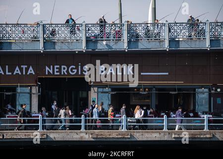 Le 23 octobre 2021, des touristes et des citoyens turcs à Istanbul, la plus grande ville de Turquie, ont transité le détroit du Bosphore sur des bateaux-ferries pour passagers et des ferries de transfert de voiture lors d'une journée ensoleillée d'automne. Au-dessus, les pêcheurs essaient de pêcher sur le pont de Galata tandis que les visiteurs mangent dans les restaurants ci-dessous. (Photo de Diego Cupolo/NurPhoto) Banque D'Images