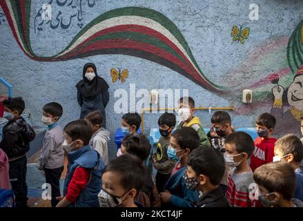 Fatemeh Hosseini, enseignante afghane, qui est venue en Iran alors qu’elle était un enfant de sept ans (Top) portant un masque facial protecteur alors que les écoliers réfugiés font la queue à l’école de Farhang le premier jour de la nouvelle année scolaire ? Dans le sud de Téhéran sur 1 novembre 2021. L'école de Farhang a fondé en 2000 par le réfugié afghan Nader Mousavi qui a obtenu une maîtrise en sociologie de l'Université de Téhéran, pour les enfants réfugiés afghans, Et maintenant deux ans après le début de l'épidémie de COVID-19 en Iran, où l'école fonctionnait à temps partiel, elle a commencé à fonctionner à temps plein et à l'Afghanistan Banque D'Images