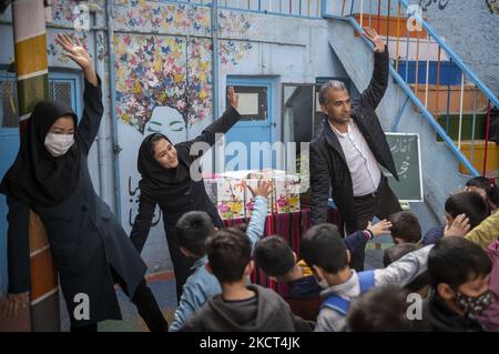 Fondateur et directeur d'école de l'école afghane Farhang, Nader Mousavi (R) enseignantes afghanes Roghayeh Hasani (C) et Fatemeh Hosseini exercice avec des écoliers réfugiés le premier jour de la nouvelle année scolaire? Dans le sud de Téhéran sur 1 novembre 2021. L'école de Farhang a fondé en 2000 par le réfugié afghan Nader Mousavi qui a obtenu une maîtrise en sociologie de l'Université de Téhéran, pour les enfants réfugiés afghans, Et maintenant deux ans après le début de l'épidémie de COVID-19 en Iran, où l'école fonctionnait à temps partiel, elle a commencé à travailler à temps plein et à l'école afghane Banque D'Images