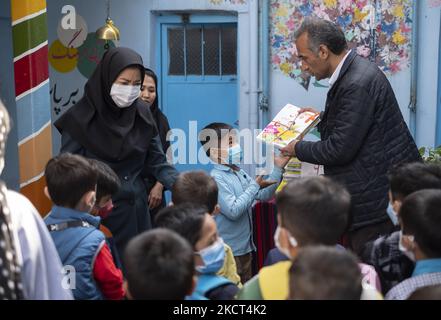 Fondateur et directeur d'école de l'école afghane Farhang, Nader Mousavi (R) remet des livres scolaires à un élève réfugié afghan le premier jour de la nouvelle année scolaire? Dans le sud de Téhéran sur 1 novembre 2021. L'école de Farhang a fondé en 2000 par le réfugié afghan Nader Mousavi qui a obtenu une maîtrise en sociologie de l'Université de Téhéran, pour les enfants réfugiés afghans, Et maintenant deux ans après le début de l'épidémie de COVID-19 en Iran, où l'école fonctionnait à temps partiel, elle a commencé à fonctionner à temps plein et les écoliers et les écoliers afghans peuvent aller à l'école. F Banque D'Images