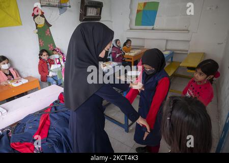 Une enseignante afghane, Mahboobeh Mohammadi-32 née en Iran, vérifie la taille d'un uniforme scolaire pour une jeune fille réfugiée afghane dans une salle de classe à l'école de Farhang le premier jour de la nouvelle année scolaire? Dans le sud de Téhéran sur 1 novembre 2021. L'école de Farhang a fondé en 2000 par le réfugié afghan Nader Mousavi qui a obtenu une maîtrise en sociologie de l'Université de Téhéran, pour les enfants réfugiés afghans, Et maintenant deux ans après le début de l'épidémie de COVID-19 en Iran, où l'école fonctionnait à temps partiel, elle a commencé à travailler à temps plein et à l'école afghane Banque D'Images