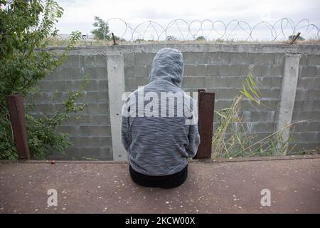 Réfugié afghan qui attend le prochain train, assis sur une voiture devant le barbelé. Les réfugiés et les migrants sont vus à la jonction des chemins de fer et des vieux wagons abandonnés qui vivent et dorment temporairement à Dialogi, près de Thessalonique. Les demandeurs d'asile venant principalement d'Afghanistan attendent que des trains de marchandises sautent et se déplacent vers Idomeni qui mène au nord de la Macédoine et à la Serbie, suivant la route des Balkans vers l'Europe. La plupart d’entre eux ont marché de Turquie vers la Grèce ou certains passeurs de voitures. Thessalonique Grèce sur 6 novembre 2021 (photo de Nicolas Economou/NurPhoto) Banque D'Images