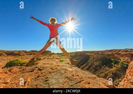 Concept de liberté de déplacement. Randonnée pédestre fille sautant à Kings Canyon dans Red Centre Outback. Faites un saut parmi les formations de grès dans le parc national de Watarrka avec Banque D'Images