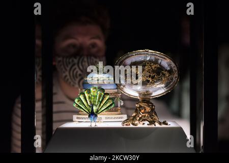 LONDRES, ROYAUME-UNI - 17 NOVEMBRE 2021 : un membre du personnel regarde l'œuf de Peacock (R) et le berceau avec l'œuf de Garlands lors d'une séance photo pour la prochaine exposition 'Faberge à Londres: Romance to Revolution' au V&A (20 novembre 2021 – 8 mai 2022), le 17 novembre 2021 à Londres, en Angleterre. La grande exposition du V&A avec plus de 200 objets exposés, dont une collection d’œufs de Pâques impériaux, explorera le savoir-faire du maître-d’œuvre russe Carl Faberge et la nature anglo-russe de son entreprise. (Photo de Wiktor Szymanowicz/NurPhoto) Banque D'Images