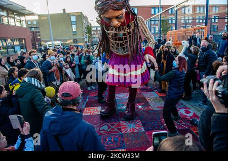 La marionnette géante 'Little Amal', une jeune fille syrienne de neuf ans et de plus de 11 mètres de haut, regarde le tapis spécial qu'un groupe d'enfants lui a fait, lors de sa visite au théâtre multiculturel 'de Vaillant', à la Haye, sur 17 novembre 2021. (Photo par Romy Arroyo Fernandez/NurPhoto) Banque D'Images