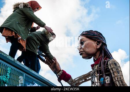 La marionnette géante « Little Amal », une jeune fille syrienne de neuf ans et de plus de 11 mètres de haut, donne la main à un groupe d'enfants debout sur un conteneur de navire, lors de sa visite au théâtre multiculturel « de Vaillant », à la Haye, sur 17 novembre 2021. (Photo par Romy Arroyo Fernandez/NurPhoto) Banque D'Images