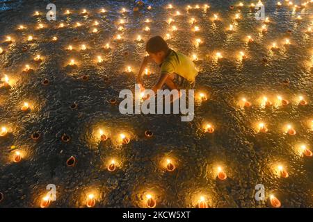 Un petit enfant est vu allumer des lampes à l'huile à un ghat de rivière à l'occasion de Dev Deepavali à Kolkata , Inde , le 19 novembre 2021 .Dev Deepavali est un festival hindou qui est célébré sur Karthik Purnima , 15 jours après Diwali et est considéré comme Diwali de Dieu . Les dévotés allument une lampe à huile sur les côtés du Gange pour rendre hommage à la rivière et à sa Déesse. (Photo par Debarchan Chatterjee/NurPhoto) Banque D'Images