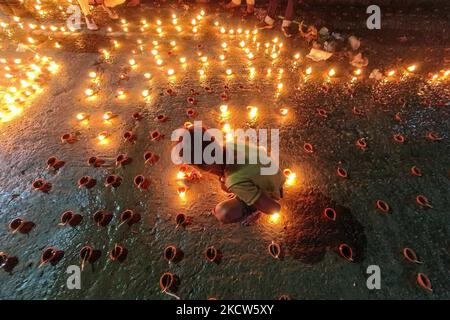 Un petit enfant est vu allumer des lampes à l'huile à un ghat de rivière à l'occasion de Dev Deepavali à Kolkata , Inde , le 19 novembre 2021 .Dev Deepavali est un festival hindou qui est célébré sur Karthik Purnima , 15 jours après Diwali et est considéré comme Diwali de Dieu . Les dévotés allument une lampe à huile sur les côtés du Gange pour rendre hommage à la rivière et à sa Déesse. (Photo par Debarchan Chatterjee/NurPhoto) Banque D'Images