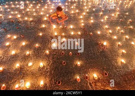 Un petit enfant est vu allumer des lampes à l'huile à un ghat de rivière à l'occasion de Dev Deepavali à Kolkata , Inde , le 19 novembre 2021 .Dev Deepavali est un festival hindou qui est célébré sur Karthik Purnima , 15 jours après Diwali et est considéré comme Diwali de Dieu . Les dévotés allument une lampe à huile sur les côtés du Gange pour rendre hommage à la rivière et à sa Déesse. (Photo par Debarchan Chatterjee/NurPhoto) Banque D'Images