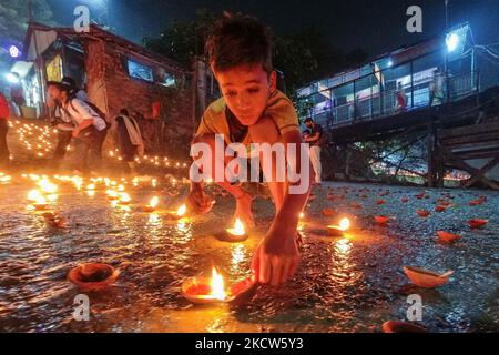 Un petit enfant est vu allumer des lampes à l'huile à un ghat de rivière à l'occasion de Dev Deepavali à Kolkata , Inde , le 19 novembre 2021 .Dev Deepavali est un festival hindou qui est célébré sur Karthik Purnima , 15 jours après Diwali et est considéré comme Diwali de Dieu . Les dévotés allument une lampe à huile sur les côtés du Gange pour rendre hommage à la rivière et à sa Déesse. (Photo par Debarchan Chatterjee/NurPhoto) Banque D'Images