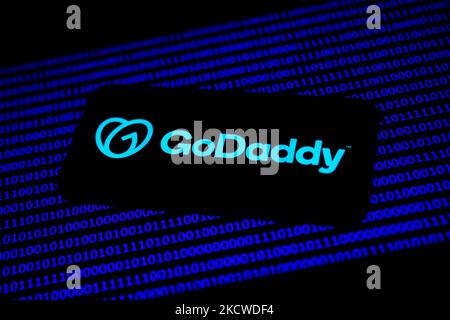 Le logo GoDaddy affiché sur un écran de téléphone et le code binaire affiché sur un écran d'ordinateur portable sont vus dans cette illustration prise à Cracovie, Pologne sur 22 novembre 2021. (Photo de Jakub Porzycki/NurPhoto) Banque D'Images