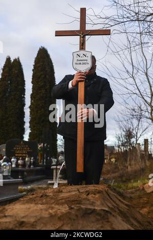 Un travailleur d'un service d'enterrement met un crucifix avec plaque NN sur une tombe d'un homme inconnu, probablement un migrant, qui a été trouvé mort dans une forêt sur 19 septembre par la frontière entre la Pologne et le Bélarus. Sokolka, Pologne sur 22 novembre 2021. Un homme a été enterré au cimetière catholique mais un prêtre n'a pas conduit de rites funéraires car il n'y avait aucune preuve de ce qui était la dénomination du défunt, malgré qu'une Sainte Bible a été trouvée par le corps. (Photo de Beata Zawrzel/NurPhoto) Banque D'Images