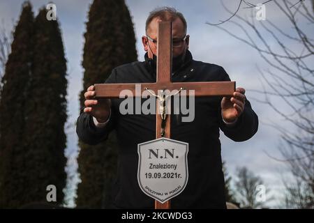 Un travailleur d'un service d'enterrement met un crucifix avec plaque NN sur une tombe d'un homme inconnu, probablement un migrant, qui a été trouvé mort dans une forêt sur 19 septembre par la frontière entre la Pologne et le Bélarus. Sokolka, Pologne sur 22 novembre 2021. Un homme a été enterré au cimetière catholique mais un prêtre n'a pas conduit de rites funéraires car il n'y avait aucune preuve de ce qui était la dénomination du défunt, malgré qu'une Sainte Bible a été trouvée par le corps. (Photo de Beata Zawrzel/NurPhoto) Banque D'Images