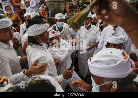 L'homme hindou balinais tente de se poignarder avec le traditionnel dagger de Keris pendant qu'il est en transe pendant le rituel sacré de Ngerebong, au milieu de la pandémie COVID-19 dans le village de Kesiman, Denpasar, Bali, Indonésie sur 28 novembre 2021. Pour la première fois pendant la pandémie, le rituel tenu en cortège complète puisqu'on croit qu'il fait des malheurs et apporte des bénis dans le village ainsi que dans l'univers. (Photo de Johannes Christo/NurPhoto) Banque D'Images