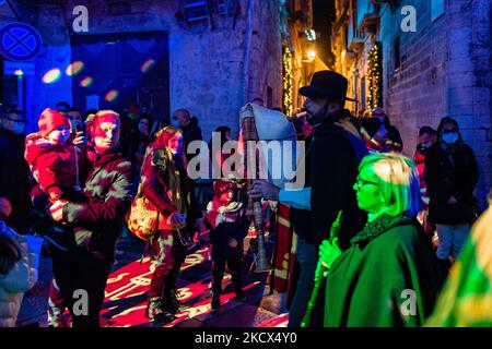 Les gens écoutent la musique populaire de deux cornemuses avec la Piazza Duomo et les bâtiments environnants illuminés par les projections des lumières de Noël sur la Piazza Duomo à Bisceglie le 2 décembre 2021. L'Association Borgo Antico, pour annoncer le calendrier des événements dans le centre historique de Bisceglie pour les prochaines vacances, a invité tous les citoyens à découvrir ensemble une surprise magique qui a officiellement lancé les initiatives de Noël de cette année. Sur la Piazza Duomo, il a donné aux adultes et aux enfants un spectacle qui a transformé la face de la cathédrale et les bâtiments qui l'entourent en un plac de rêve Banque D'Images