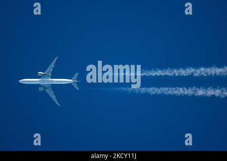 Un avion blanc volant à 40,000 pieds dans le ciel bleu pendant une journée ensoleillée au-dessus de l'Europe, un vol pendant une journée d'hiver claire. L'illustration du symbole de l'avion à grand-corps survolant sans logo imprimé sur le dessous du ventre du fuselage laisse derrière lui des contrailles ou un sentier de condensation, une ligne de vapeur blanche. L'industrie de l'aviation et le trafic de passagers sont en phase de phase avec une période difficile avec la pandémie du coronavirus Covid-19 ayant un impact négatif sur l'industrie du voyage d'affaires avec la crainte d'une aggravation de la situation en raison de la nouvelle mutation de la variante Omega. Eindhoven, pays-Bas sur D. Banque D'Images