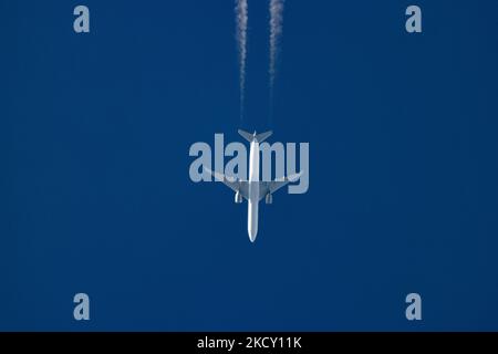 Un avion blanc volant à 40,000 pieds dans le ciel bleu pendant une journée ensoleillée au-dessus de l'Europe, un vol pendant une journée d'hiver claire. L'illustration du symbole de l'avion à grand-corps survolant sans logo imprimé sur le dessous du ventre du fuselage laisse derrière lui des contrailles ou un sentier de condensation, une ligne de vapeur blanche. L'industrie de l'aviation et le trafic de passagers sont en phase de phase avec une période difficile avec la pandémie du coronavirus Covid-19 ayant un impact négatif sur l'industrie du voyage d'affaires avec la crainte d'une aggravation de la situation en raison de la nouvelle mutation de la variante Omega. Eindhoven, pays-Bas sur D. Banque D'Images